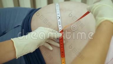 医生测量怀孕女孩特写的腹部。 孕妇肚子`的周长。